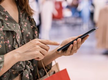 kobieta trzymająca smartfon w sklepie